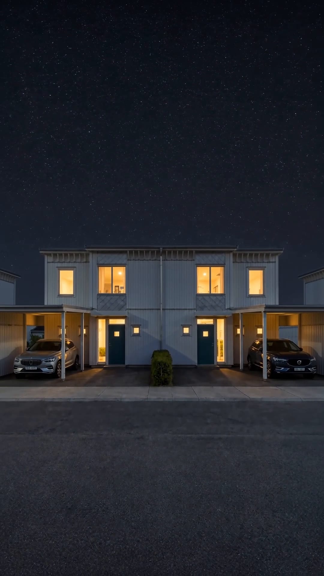 Stillbild ur filmen: Parhuset rakt framifrån en kväll, med tända fönster, carportar på båda sidor och stjärnhimmel över taket.